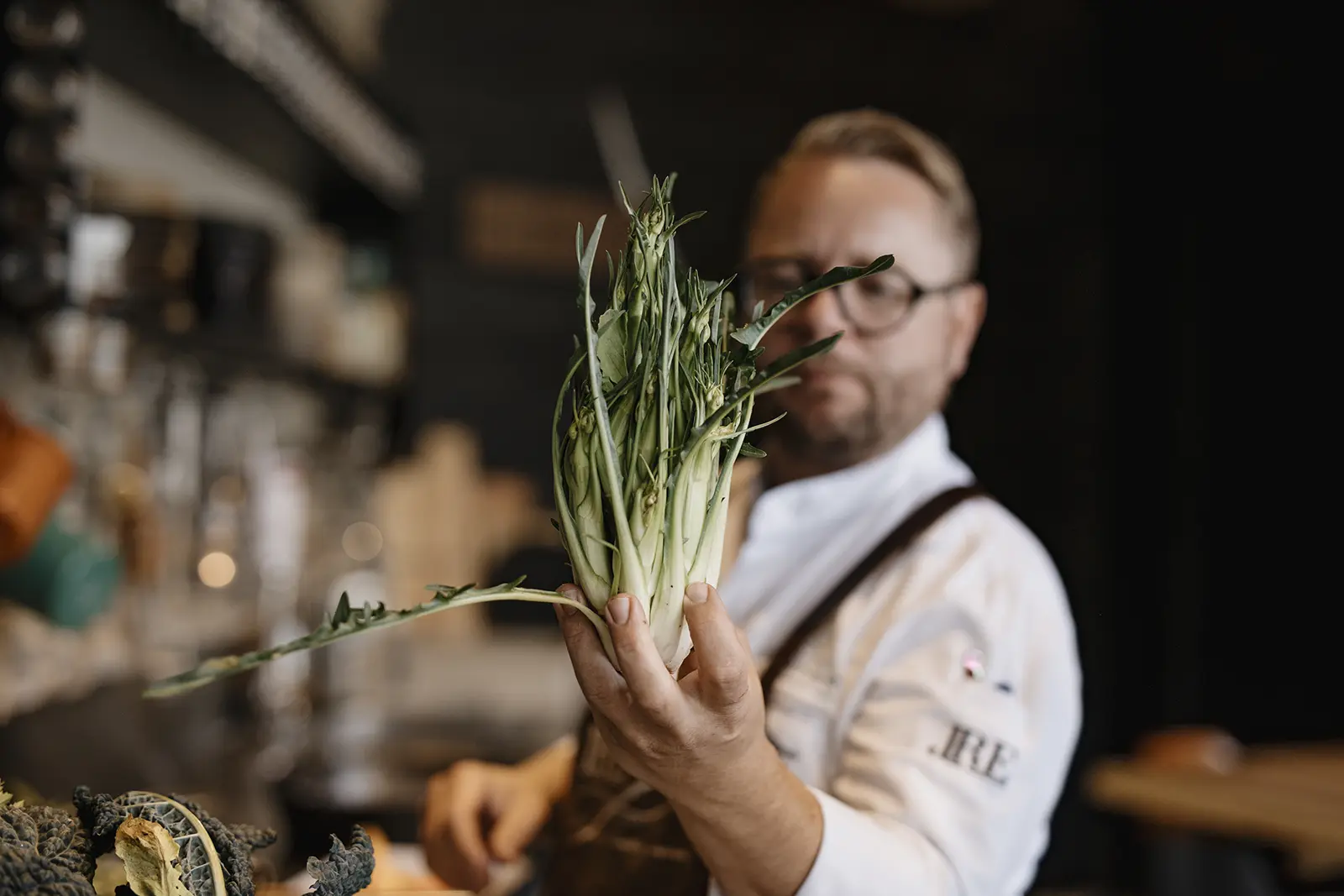 Ein Koch in weißem Gewand hält einen Kohlrabi in die Kamera.