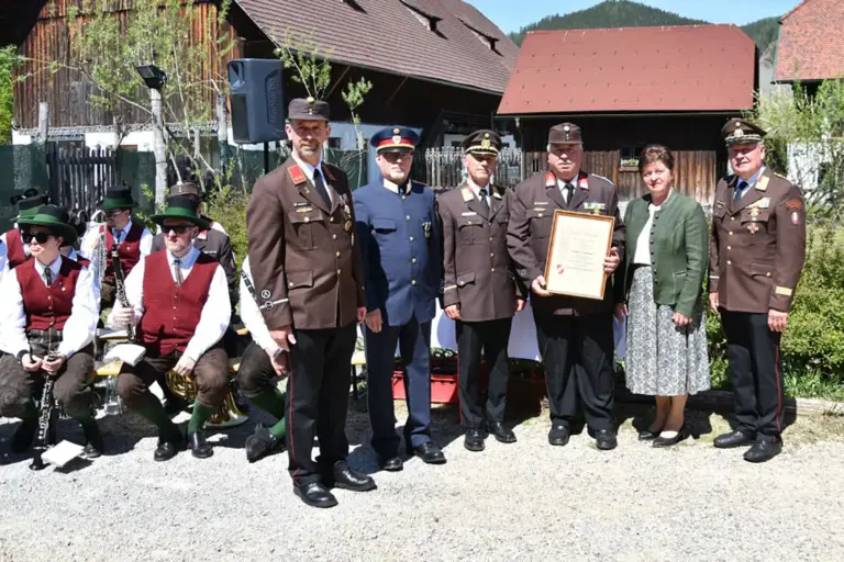 Eine Frau mit Feuerwehrmännern. Danemen sitzen ein paar Musikanten.