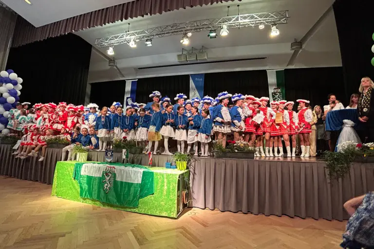 Kinder und Jugendliche in Gardeuniformen auf einer Bühne.
