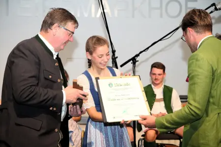 Langenwang: Harmonika-Award für Klara Mißebner Ein junge Musikerin erhält eine Urkunde von zwei Männern.