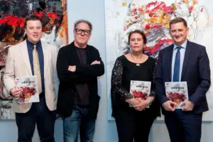 Drei Männer und eine Frau vor zwei Gemälden von Georg Brandner.