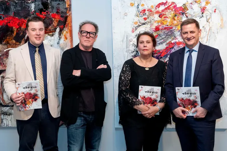 Drei Männer und eine Frau vor zwei Gemälden von Georg Brandner.