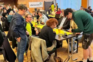 Menschen sitzen an mehreren Tischen und reden angeregt miteinander.