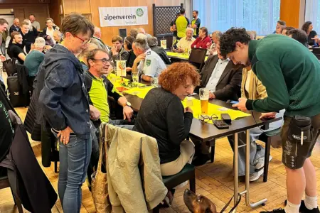 Menschen sitzen an mehreren Tischen und reden angeregt miteinander.