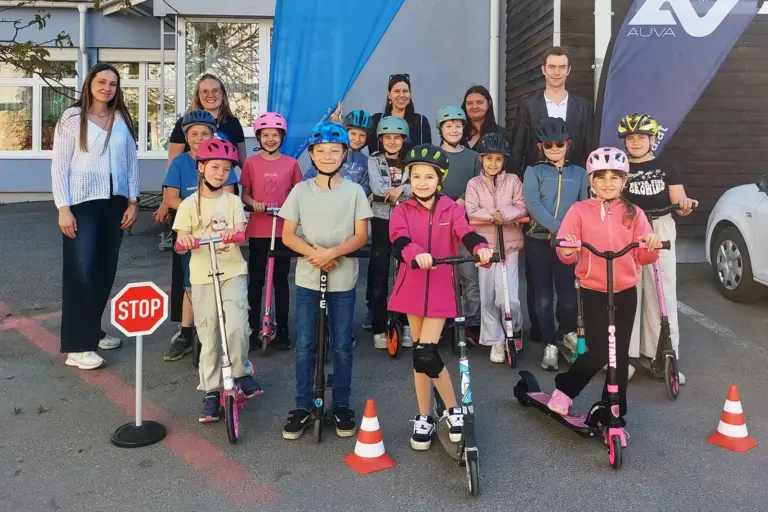 Bezirk Leoben: 26 Schulen, ein Themenmonat Eine Gruppe von Kindern mit Rollern stehen mit einigen Erwachsenen vor einem Gebäude