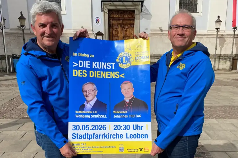 Über die Kunst des Dienens Zwei Männer in blauen Jacken halten ein Plakat