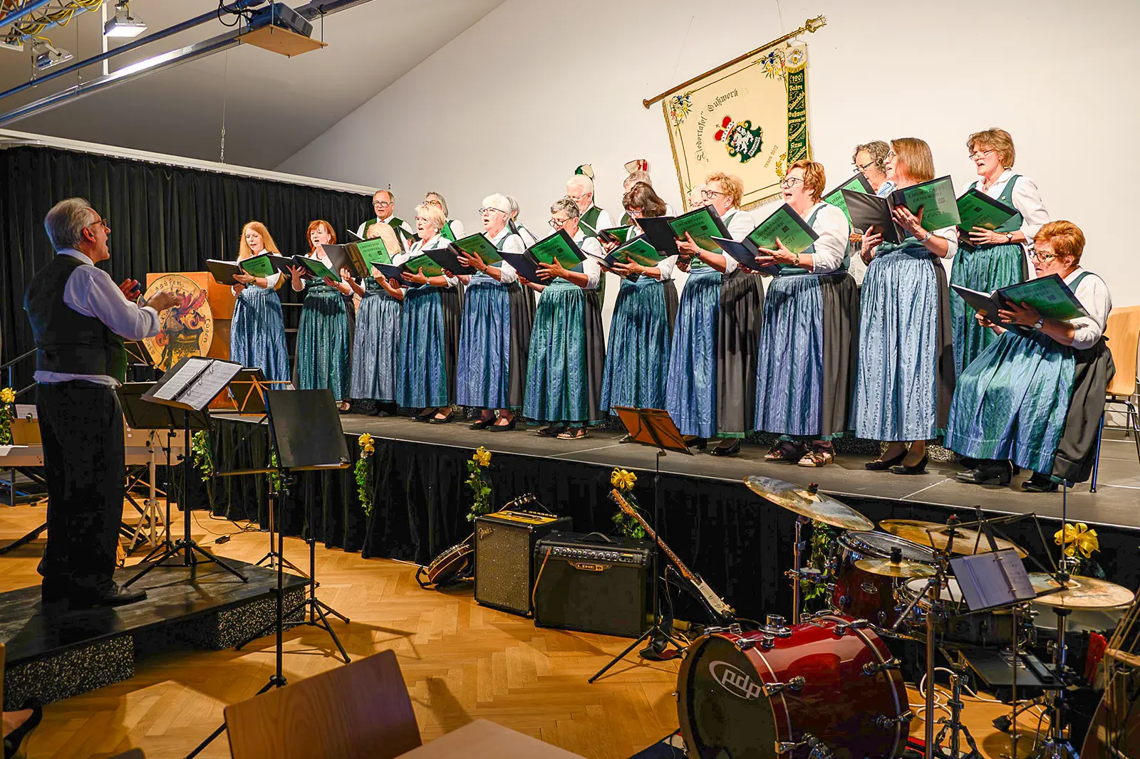 Ein Frauenchor in Tracht singt auf einer Bühne