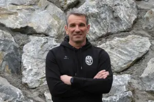 Ein Mann steht vor einer Steinwand.
