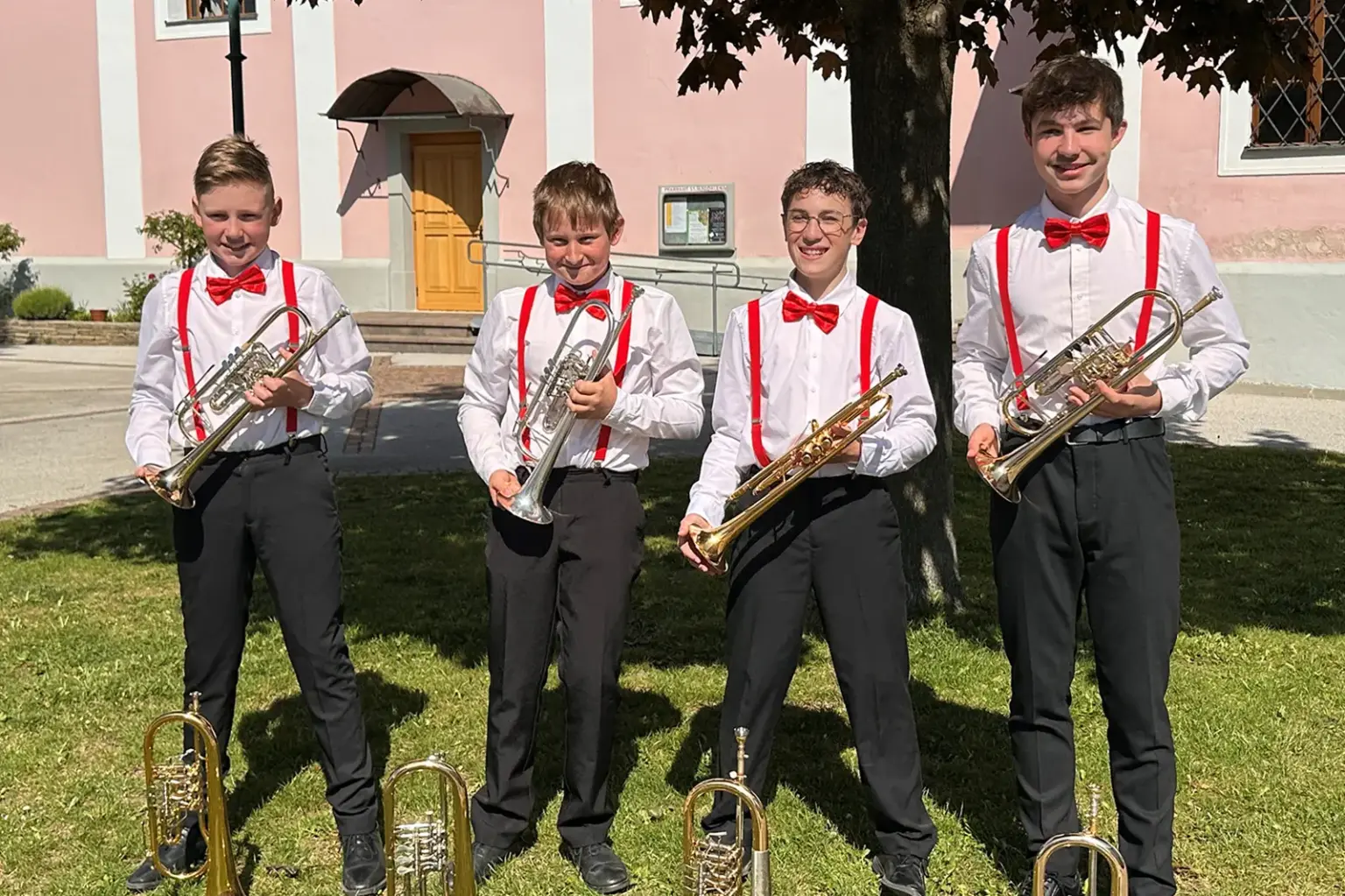 Preisgekrönte Musikjugend aus Mürzzuschlag Vier junge Burschen mit Trompeten stehen unter einem Baum