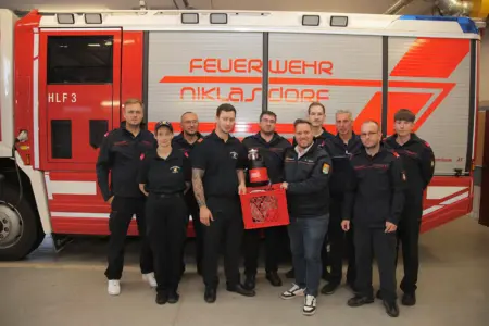 Gerätespende an die Feuerwehr Niklasdorf Mehrere Personen in Uniform stehen mit einem Gerät vor einem Feuerwehrauto