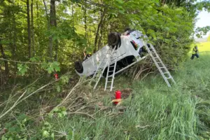 Schwerer Verkehrsunfall in Spital am Semmering Ein Fahrzeug liegt nach einem Unfall kopfüber in einem bewaldeten Hangbereich. Feuerwehrkräfte und Leitern sind im Einsatz, während rund um das Auto Äste und umgeknickte Sträucher zu sehen sind.