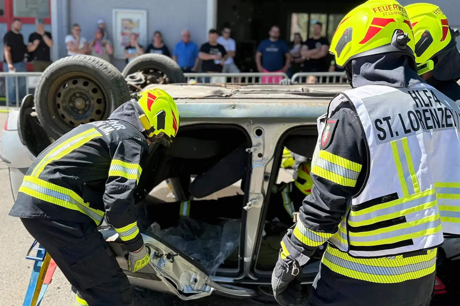 Tag der offenen Tür bei der Feuerwehr St. Lorenzen Mehrere Feuerwehrmänner stehen vor einem auf dem Dach liegenden Auto