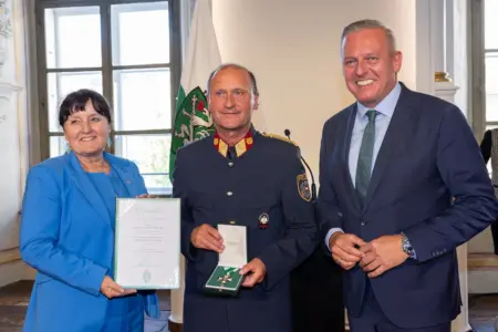 Eine Frau und zwei Männer bei einer Urkundenverleihung.