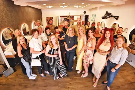 Eine Gruppe von Personen steht mit Gläsern in der Hand in einem Friseursalon