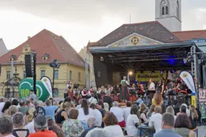 Eine Open-Air-Bühne mit MusikerInnen und vielen ZuschauerInnen davor