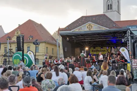 Eine Open-Air-Bühne mit MusikerInnen und vielen ZuschauerInnen davor
