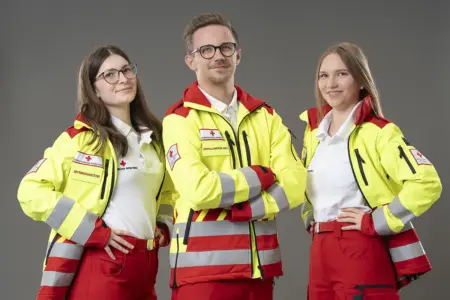 Infoabend beim Roten Kreuz Bruck Ein Mann und zwei Frauen in Rotkreuz-Uniformen stehen vor einer grauen Wand