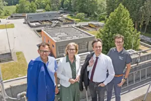 Drei Männer und eine Frau stehen auf einem Dach vor einem Betriebsgelände