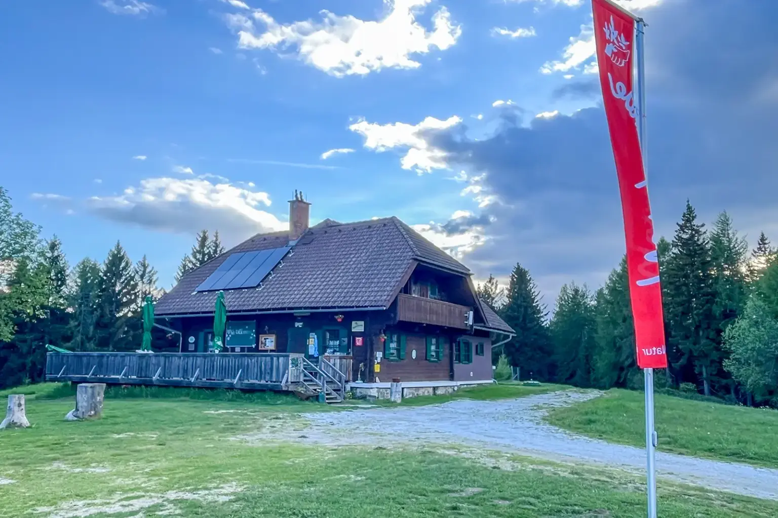 Ein Schutzhaus mit Terrasse und eine rote Flagge auf einem Berg