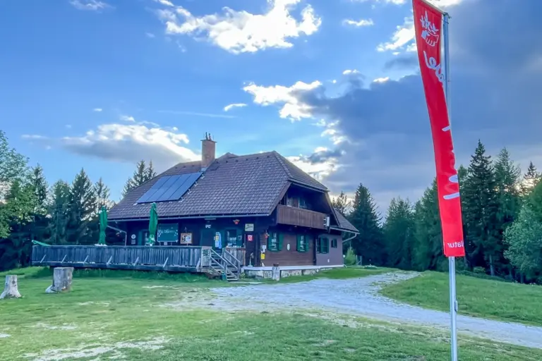 Ein Schutzhaus mit Terrasse und eine rote Flagge auf einem Berg