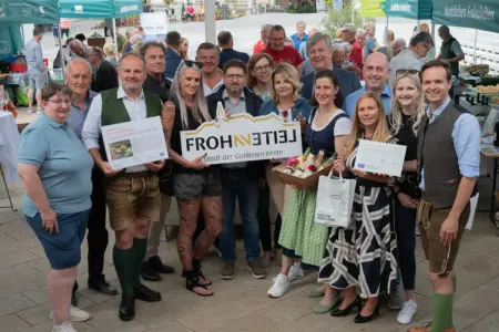 Frohnleiten: Premiere für neues Bauernmarktkonzept Eine Gruppe von Personen steht auf einem großen Platz unter einem großen Schirm