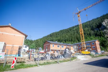 Drei in Bau befindliche Häuser in Ziegelbauweise, auf dem Gelände Baumaterial, Baumaschinen und ein Kran