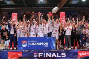 Die Basketballmannschaft aus Kapfenberg feiert gemeinsam mit Betreuern und Fans den Meistertitel der Superliga 2026. Spieler mit Medaillen jubeln auf dem Siegerpodest und halten den Meisterpokal in die Höhe, während das Publikum im Hintergrund mitfeiert.