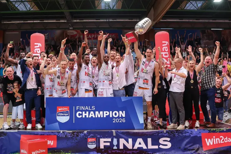 Kapfenberg Bulls sind Meister Die Basketballmannschaft aus Kapfenberg feiert gemeinsam mit Betreuern und Fans den Meistertitel der Superliga 2026. Spieler mit Medaillen jubeln auf dem Siegerpodest und halten den Meisterpokal in die Höhe, während das Publikum im Hintergrund mitfeiert.