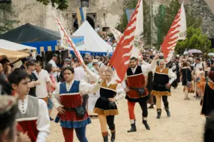 Eine Gruppe von Personen in mittelalterlichen Kostümen marschieren mit Fahnen durch einen Burghof