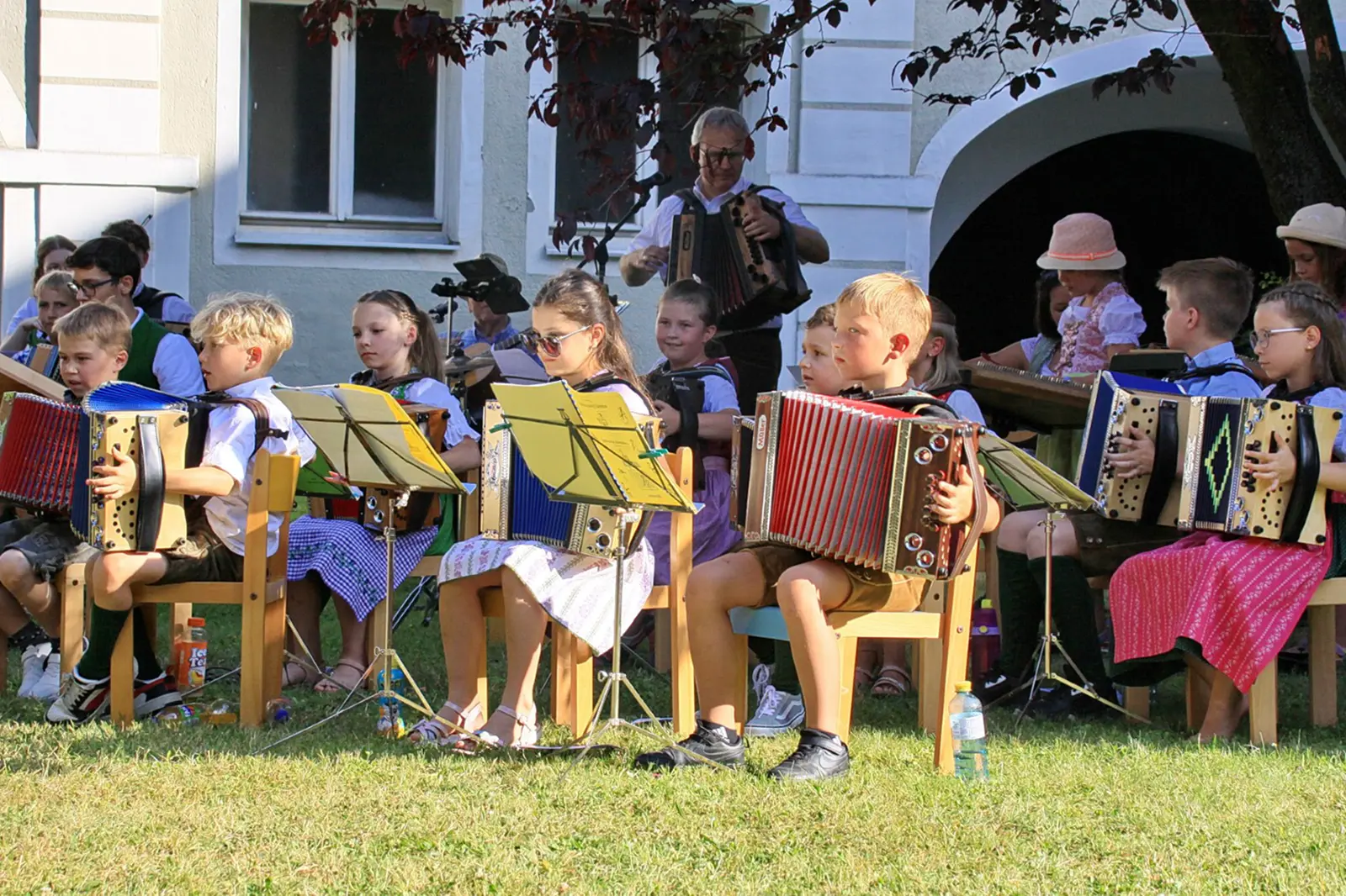Kinder in Tracht spielen Harmonika auf einer Wiese