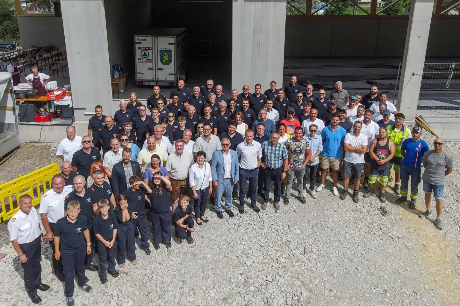 Gleichenfeier beim Kindberger Rüsthaus Eine große Gruppe von Personen, zum Teil in Uniform, steht vor einem Rohbau