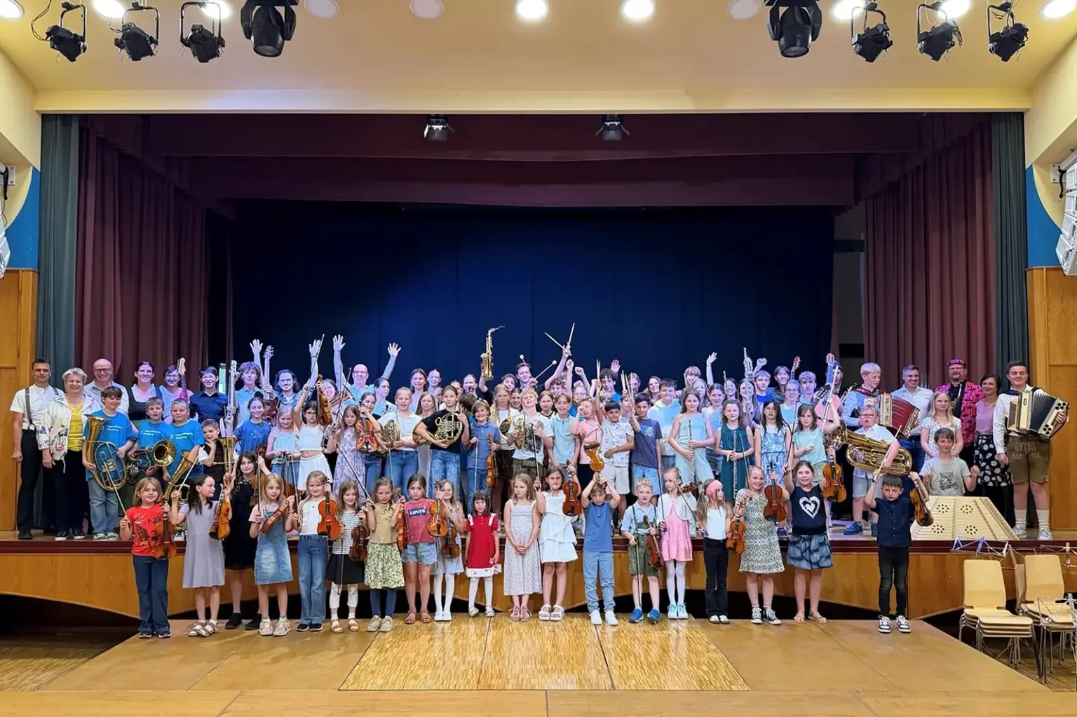 Gelungenes Abschlusskonzert in Kindberg Eine große Gruppe von Kindern und Jugendlichen mit Musikinstrumenten steht auf und vor einer Bühne