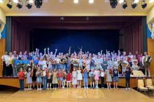 Eine große Gruppe von Kindern und Jugendlichen mit Musikinstrumenten steht auf und vor einer Bühne