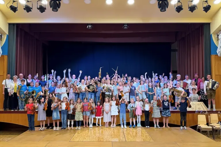 Gelungenes Abschlusskonzert in Kindberg Eine große Gruppe von Kindern und Jugendlichen mit Musikinstrumenten steht auf und vor einer Bühne