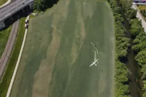 Ein Flugzeug auf einem Feld zwischen einer Schnellstraße und einem Fluss