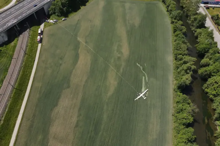 Ein Flugzeug auf einem Feld zwischen einer Schnellstraße und einem Fluss
