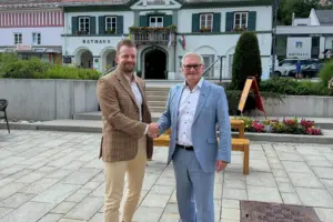Zwei Männer schütteln sich vor einem Rathaus die Hand