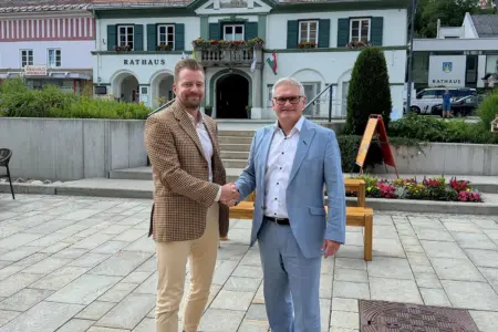 Zwei Männer schütteln sich vor einem Rathaus die Hand