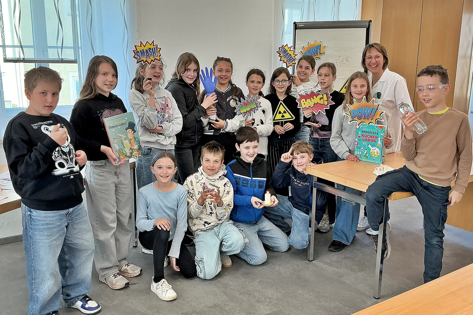 VolksschülerInnen mit verschiedenen Büchern und Objekten in den Händen.