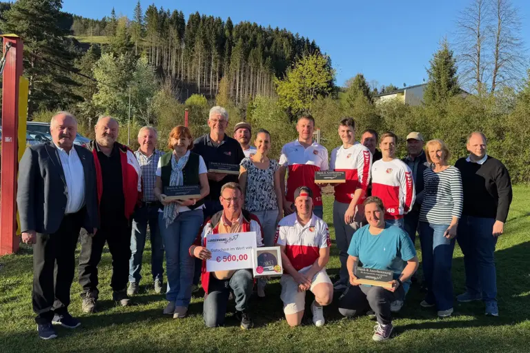 Eine Gruppe von Personen steht mit Trophäen auf einer Wiese