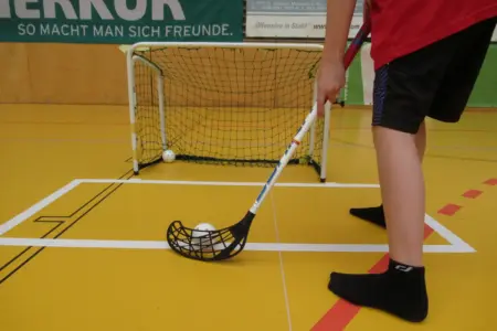 Ein Kind spielt Floorball in einer Halle