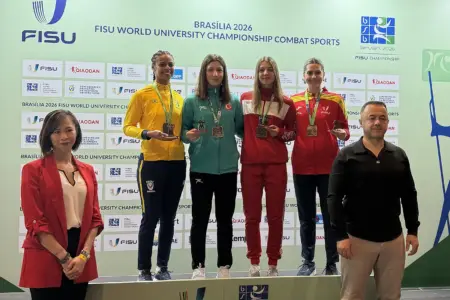 Vier Medaillengewinnerinnen stehen bei einer Siegerehrung auf dem Podest vor einer FISU-Rückwand und halten ihre Medaillen. Zwei weitere Personen stehen vor dem Podest.