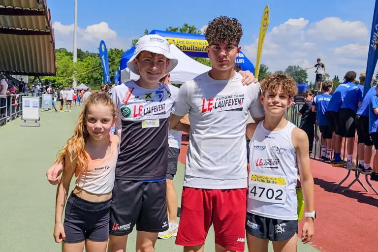 Junge Läuferinnen und Läufer posieren beim Lidl-Schullauf vor dem Start- und Zielbereich für ein Erinnerungsfoto.