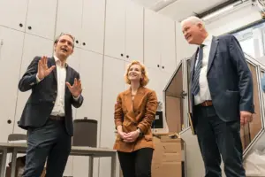 Zwei Männer und eine Frau unterhalten sich in einem großen Raum