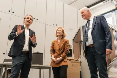 Ministerin zu Gast in der Leobener Uni Zwei Männer und eine Frau unterhalten sich in einem großen Raum