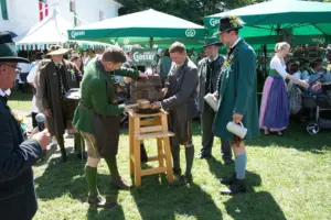 Mehrere Personen in Tracht beim Bieranstich auf einer Festwiese