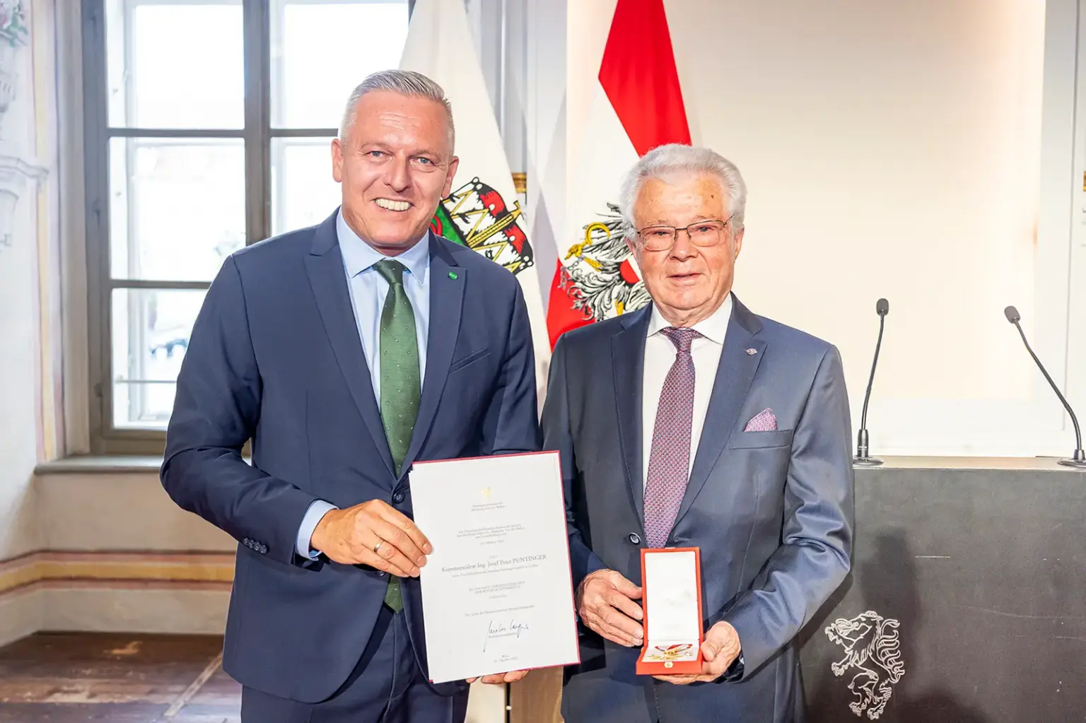 Zwei Männer mit Anzug und Krawatte bei einer Preisverleihung