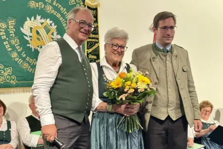 Zwei Männer und eine Frau mit Blumenstrauß in Tracht