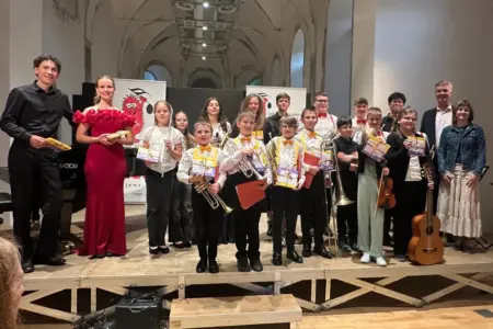 Mürzzuschlag: Konzert der PreisträgerInnen Mehrere junge MusikerInnen mit Geschenkspäckchen stehen mit Erwachsenen auf einer Bühne