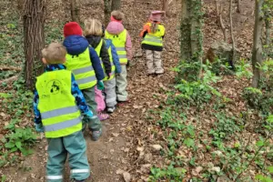 Fünf Kinder gehen mit Schutzwesten durch einen Wald